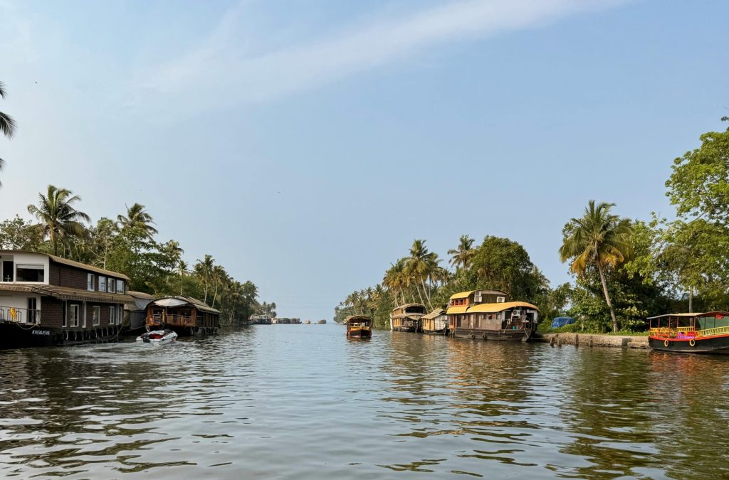 Houseboats floating on the tranquil Kerala backwaters under a clear blue sky.
