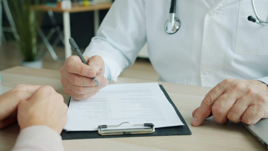 Doctor writing on a patient's chart